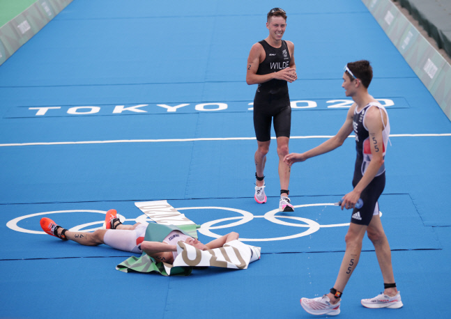 트라이애슬론 남자 개인전 결승선을 제일 먼저 통과한 크리스티안 블룸멘펠트(왼쪽 첫 번째)가 바닥에 쓰러져 있다. 도쿄 | 로이터연합뉴스