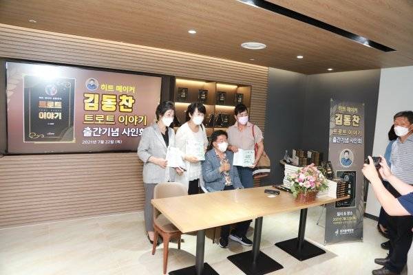 작사가 김동찬(왼쪽에서 세 번째 앉은 사람)이 22일 경남 거제시 거붕백병원에서 저서 ‘트로트 이야기’ 출판기념회를 열고 팬들과 기념촬영을 하고 있다. 사진|김동찬 제공