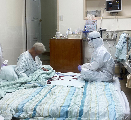 삼육서울병원 간호사 이수련(29)씨가 지난해 8월 방호복을 입은 채 코로나19 환자 박모 할머니(93)와 화투 놀이를 하고 있다. [사진 = 대한간호협회 제공]