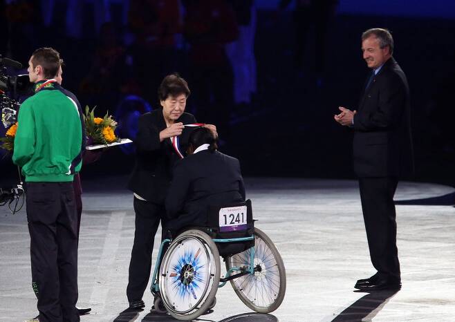런던 패럴림픽 폐회식에서 메달 걸어주는 황연대 여사 황연대 여사가 2012 런던 패럴림픽 폐막식에서 황연대 성취상 수상자인 아일랜드의 뇌성마비 육상선수 마이클 맥킬럽(왼쪽)과 여자 수상자 매리 나쿠미차 자카요에게 순금 메달을 걸어주고 있다. [연합뉴스 자료사진]