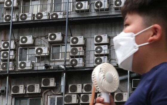 (서울=뉴스1) 이성철 기자 = 폭염이 계속된 8일 서울의 한 건물의 실외기 앞으로 손선풍기를 든 아이가 지나가고 있다. 2021.8.8/뉴스1