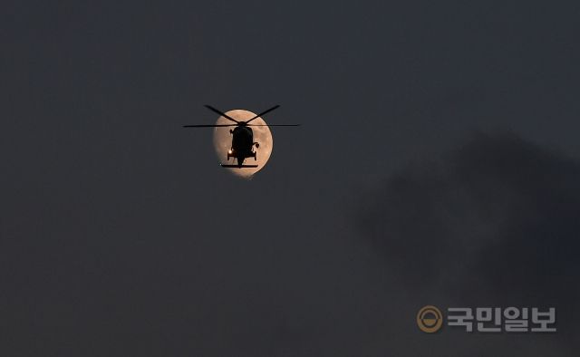 지난달 19일 인천 영종도 하늘에서 밝게 뜬 달 앞으로 해경 구조헬기가 순찰 비행을 하고 있다.