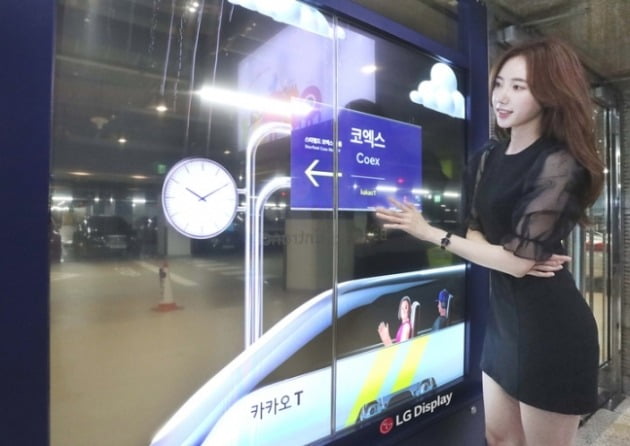 LG디스플레이 모델이 코엑스 주차장 출입문에 설치된 투명 OLED를 보고 있다. [사진=LG디스플레이 제공]
