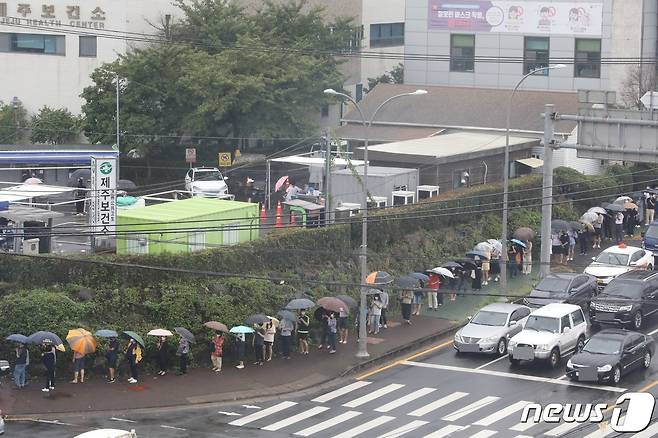 제12호 태풍 '오마이스'가 북상하는 13일 오후 제주시 도남동 제주보건소 앞에 코로나19 진단검사를 받으려는 시민들이 우산을 쓰고 줄 서 있다. 2021.8.23/뉴스1 © News1 고동명 기자