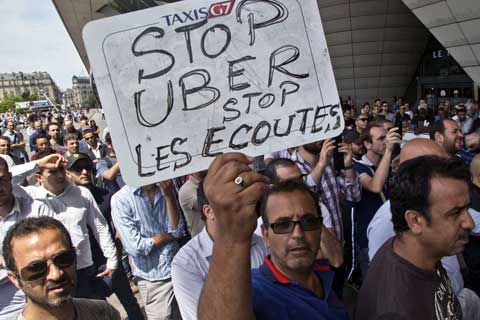 지난해 6월 프랑스 파리에서 벌어진 우버 반대 시위에서 한 택시 기사가 “우버 서비스를 중단하라”는 내용의 팻말을 들어 보이고 있다.