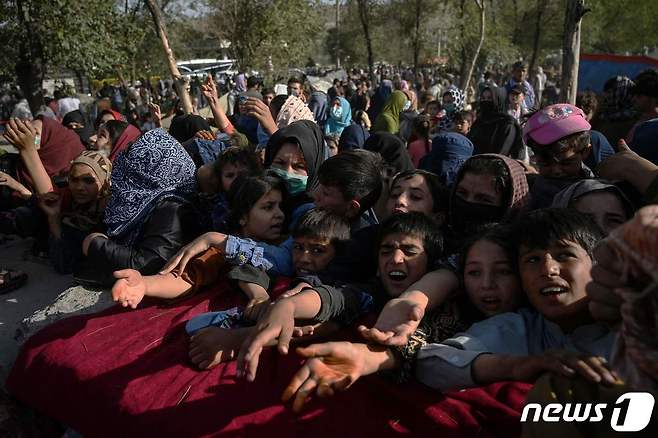9일(현지시간) 아프가니스탄 정부와 탈레반과 전쟁이 벌어지고 있는 가운데 수도 카불에서 전쟁 지역에서 피난온 어린이들이 구호 식량을 얻기 위해 손길을 내밀고 있다. 2021.08.09 © AFP=뉴스1