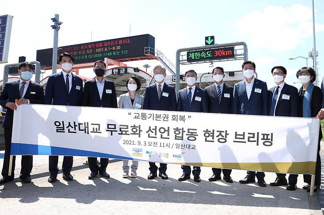 지난 3일 일산대교 요금소 앞에서 이재명 경기도지사 등이 일산대교 무료화 선언 합동 브리핑을 하고 있다. 왼쪽 두 번째부터 한준호 의원, 김주영 의원, 홍정민 의원, 이재명 지사, 정하영 김포시장, 이재준 고양시장, 박상혁 의원, 최종환 파주시장.