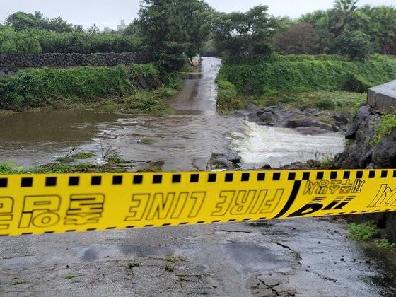 태풍 찬투의 간접 영향으로 제주에 많은 비가 내린 14일 제주시 화북천 범람으로 물에 잠긴 길에 출입 통제선이 설치돼 있다. 연합뉴스