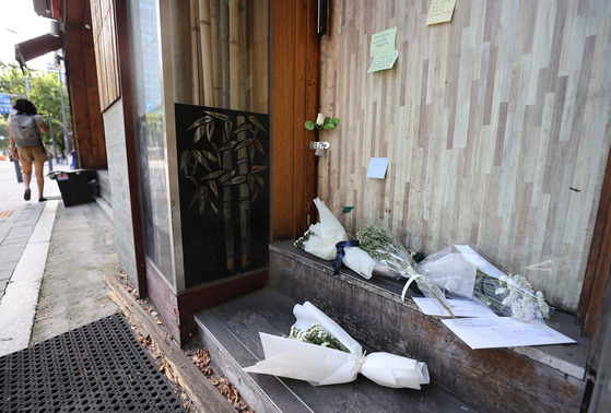 Flowers and hand-written notes are left to mourn the 57-year-old restaurant owner who was found dead Sept. 7. [YONHAP]