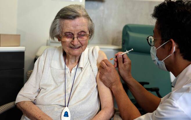 파리에서 한 고령의 여성이 지난 13일 코로나 예방 백신 3차 접종을 하고 있는 장면. 프랑스는 이날부터 요양시설에 거주하는 고령자를 대상으로 '부스터샷' 접종을 개시했다./AFP 연합뉴스