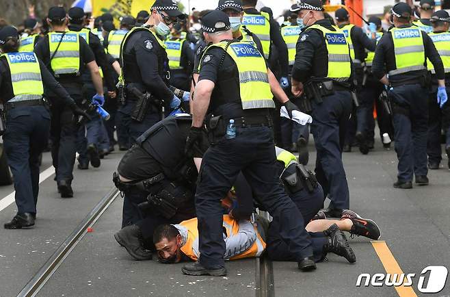 18일 호주 멜버른에서 경찰이 도시 봉쇄에 반대하는 시위대를 제압하고 있다. © AFP=뉴스1