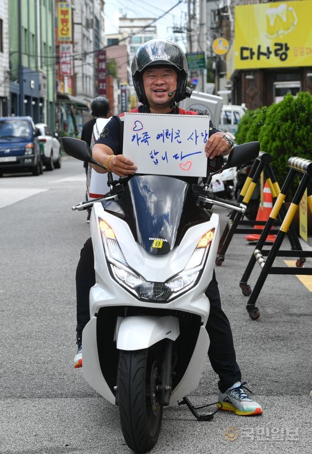 김경한 생각대로 동대문지부 대표가 지난 8일 서울 동대문구에 위치한 사무실 앞에서 가족들을 향한 메시지를 든 채 활짝 웃고 있다.