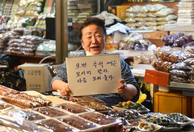 서울 종로구 광장시장의 떡집에서 근무하고 있는 오정숙 씨가 지난 7일 가족들에게 전달하는 메시지를 든 채 웃고 있다.