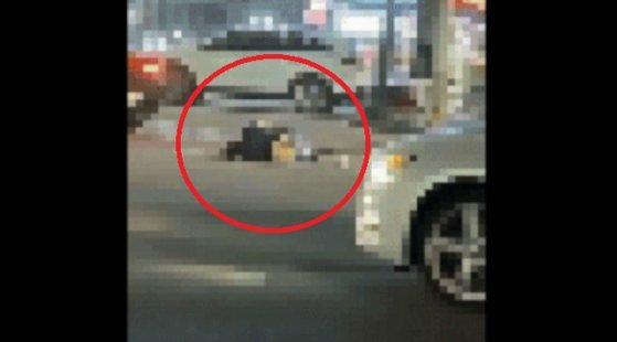 지난 5월7일 충남 서산시 갈상동 사거리에서 도로 위에 누워 있는 여성을 승용차가 밟고 지나가는 모습. [온라인 커뮤니티 ‘보배드림’ 캡처]