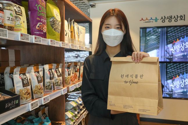 서울시 종로구에 위치한 상생상회 매장에서 현대백화점 직원이 '현대식품관 투홈' 종이 쇼핑백을 들고 있는 모습.ⓒ현대백화점