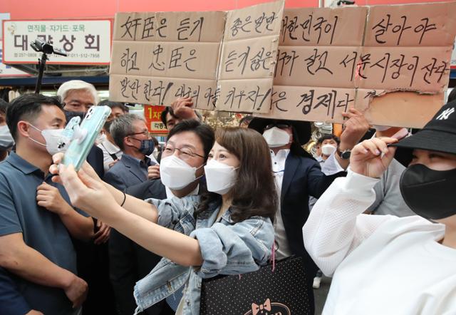 국민의힘 대선 경선 후보인 유승민(왼쪽 두 번째) 전 의원이 13일 대구 중구 서문시장을 찾아 한 시민과 기념사진을 찍고 있다. 한 지지자가 뒤에서 유승민이 충신이었음을 강조하는 글을 써서 들고 있다. 대구= 뉴스1