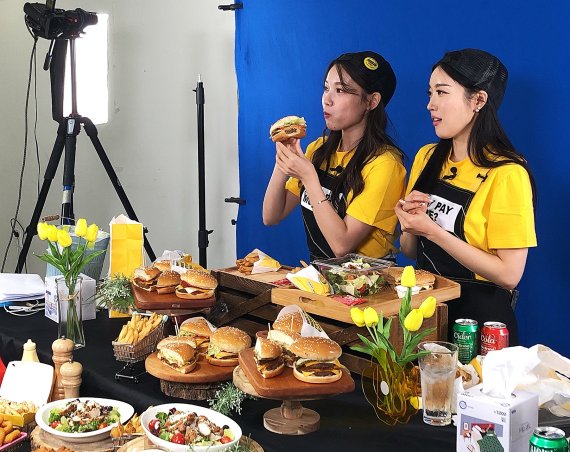 지난 18일 서울 송파구 배달의 민족 스튜디오에서 진행된 라이브 방송에서 쇼호스트들이 노브랜드 버거를 소개하고 있다. 사진=신세계푸드 제공
