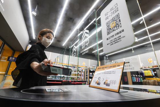 An Emart24 employee checks into an unmanned convenience store in Coex, southern Seoul, using a QR code on Thursday. Customers can enter the store after receiving a QR code when they register a credit or debit card. They can pick up products and leave the store without scanning their purchases, with payments processed automatically. [YONHAP]