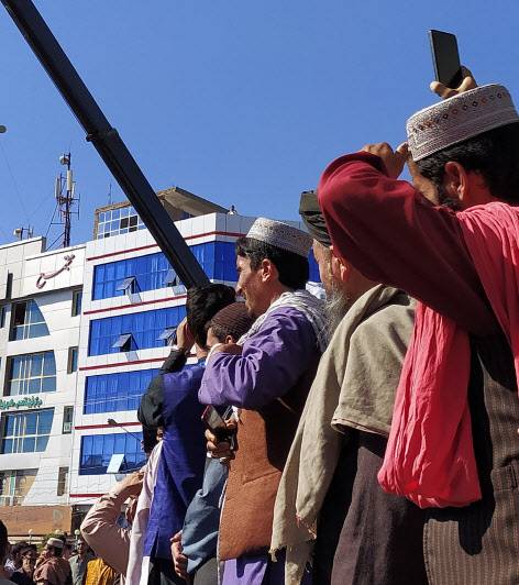 기중기에 매달린 시신을 보고 있는 아프간 주민들(사진=AFP)