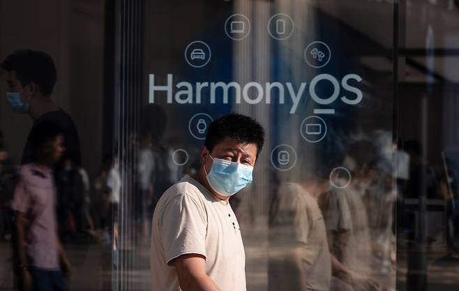 중국 상하이의 한 화웨이 매장 앞을 마스크를 쓴 남자가 지나가고 있다. 매장 앞에는 훙멍OS 광고문구가 붙어 있다. /EPA연합뉴스
