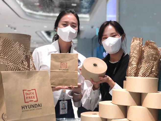 현대백화점면세점 인천공항점에서 직원들이 종이 포장재를 소개하고 있는 모습