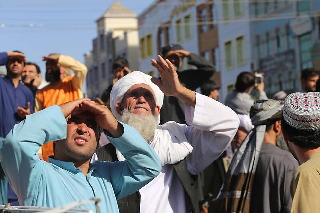 아프가니스탄 헤라트 주민들이 25일 기중기에 매달린 ‘납치범’ 주검을 올려다보고 있다. 헤라트/AP 연합뉴스
