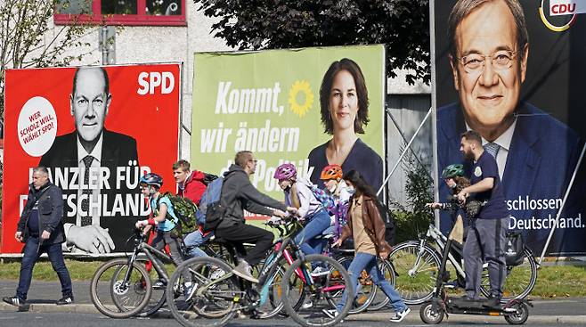 총선을 사흘 앞둔 지난 23일(현지시간) 독일 노르트라인베스트팔렌주에서 시민들이 올라프 숄츠 사민당 후보, 아날레나 베어보크 녹색당 후보, 아르민 라셰트 기민련 후보(왼쪽부터)의 선거 포스터 앞을 지나가고 있다.  겔젠키르헨 | AP연합뉴스