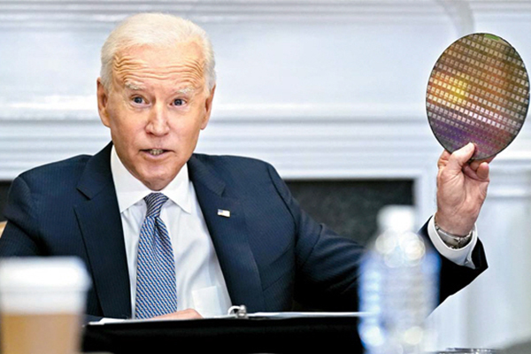 U.S. President Joe Biden holds up a silicon wafer while speaking in a virtual summit meeting with chip and auto executives at the White House in April. [Photo by Yonhap]