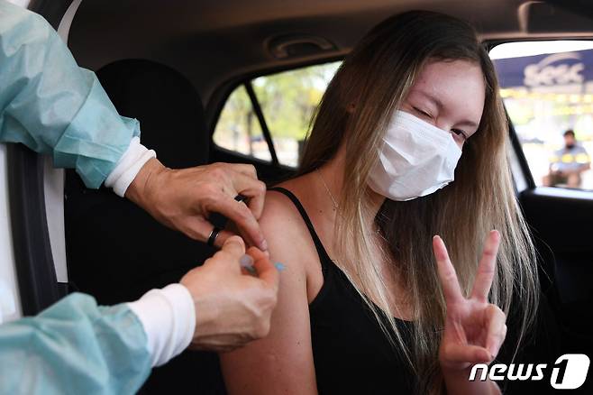 13일(현지시간) 브라질 수도 브라질리아에서 한 여성이 차안에서 신종 코로나바이러스 감염증 백신 접종을 하며 카메라를 향해 손가락 브이(V)자 포즈를 취하고 있다. 2021.09.13 © AFP=뉴스1