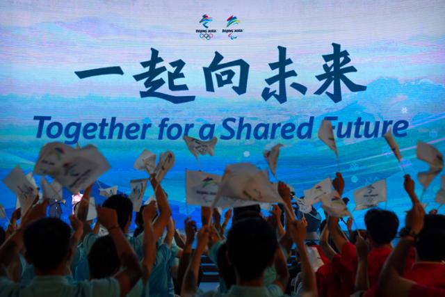 중국 베이징에서 17일 '2022 베이징 동계올림픽 및 장애인올림픽'의 구호인 '함께 공유된 미래로'(Together for a Shared Future)가 발표되자 참가자들이 환호하고 있다. 베이징=AP 뉴시스