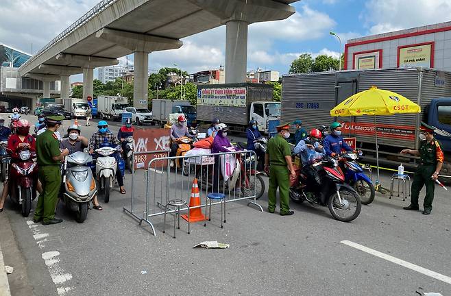 베트남의 수도 하노이의 한 검문소에서 경찰이 직장인들의 여행 허가서를 조사하고 있다. /로이터 연합뉴스