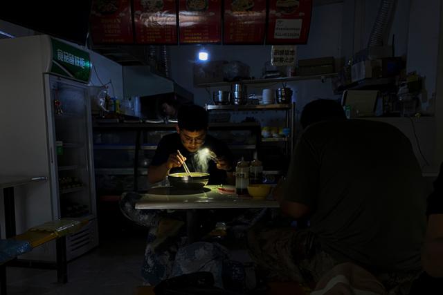 29일 중국 북동부 랴오닝성 선양에서 한 손님이 정전으로 캄캄해진 식당에서 휴대폰 불빛에 의존해 식사를 하고 있다. 선양=AP 연합뉴스