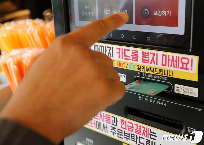 (서울=뉴스1) 김진환 기자 = 기획재정부는 다음 달부터 1인당 월 최대 10만원까지 환급해주는 상생소비지원금(카드 캐시백) 정책 세부 시행안을 발표한다. 카드 캐시백은 신용·체크카드를 2분기(4∼6월) 월평균 사용액보다 3% 이상 많이 쓰면 초과분의 10%를 월 10만원까지 환급해주는 정책으로 2분기에 자신이 가진 모든 신용·체크카드(법인카드 제외)를 합쳐 월평균 100만원을 쓴 사람이 10월에 카드로 153만원을 쓰면 월평균 금액의 3%인 3만원을 뺀 초과분 50만원의 10%인 5만원을 돌려받는 방식이다. 사진은 27일 서울 시내 한 커피 전문점에서 카드 결제 하는 모습. 2021.9.27/뉴스1