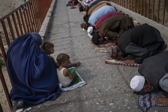 부르카를 입은 아프간 여성과 두 아이가 지난달 카불의 금요 기도 중에 구걸을 하고 있다. 연합뉴스