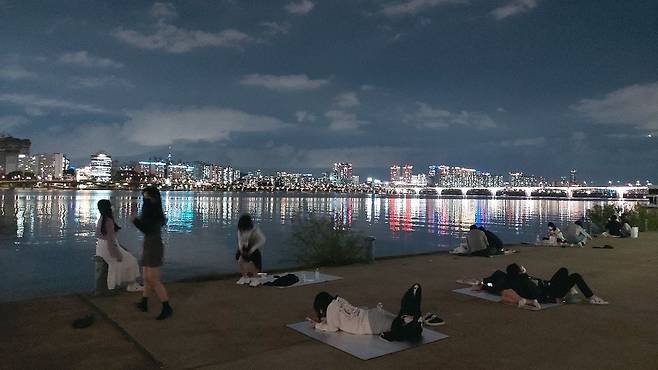 13일 오후 7시쯤 서울 영등포구 여의도한강공원. 한강 야경을 배경으로 사진을 찍기 위해 걸터앉은 시민들이 눈에 띈다. /이정수 기자