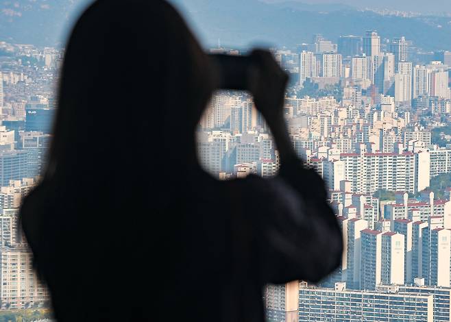 서울 영등포구 63스퀘어를 찾은 한 시민이 고층 아파트들이 빽빽히 들어선 서울 도심 풍경을 휴대전화로 찍고 있다./연합뉴스