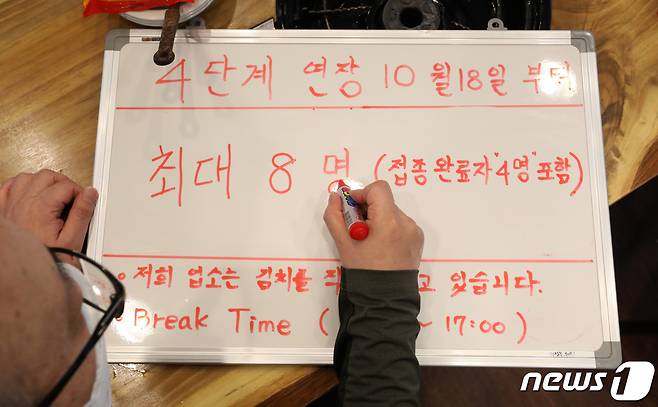 지난 15일 오후 서울시 종로구의 한 식당에서 점주가 변경될 인원제한 안내문을 작성하고 있다. 2021.10.15/뉴스1 © News1 조태형 기자