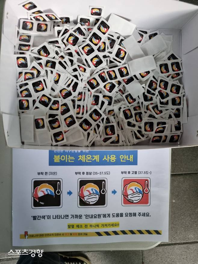 잠실구장 1층 출입구에서 매뉴얼에 따라 관객에게 부착하는 스티커. 정상체온일 때 파란스티커가 부착된다.