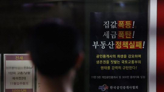 한 시민이 부동산공인중개업소 매물정보 게시판에 붙어있는 정부의 부동산 정책 규탄 포스터를 지켜보고 있다. <연합뉴스>