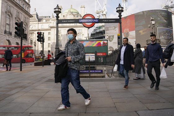 19일(현지시간) 한 영국인이 마스크를 쓰고 런던시 피카딜리 광장을 지나가고 있다. [AP=연합뉴스]