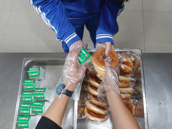 20일 울산시 중구의 한 중학교 급식실에서 도시락을 싸 오지 못한 학생이 교사로부터 빵과 우유를 건네받고 있다. 연합뉴스