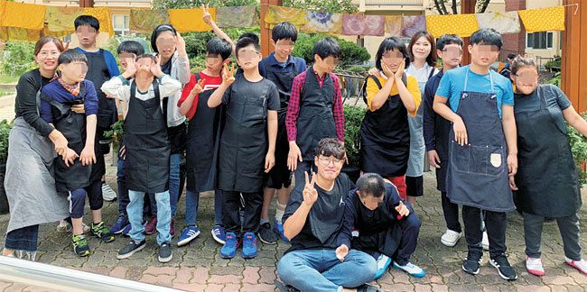 코로나19가 유행 전인 2019년 9월 27일 대구 수성구 ‘대구 남양학교’에서 김수정(오른쪽 네 번째) 교사가 동료 교사, 제자들과 함께 천연염색 체험을 한 뒤 기념사진을 찍고 있다.  초록우산어린이재단 제공