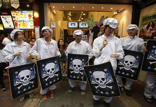2011년 5월 폭스콘 노동자 옷을 입은 대학생들이 홍콩의 한 애플 판매점 앞에서 해골이 그려진 아이패드 모형을 들고 폭스콘의 노동 환경에 대해 항의하는 시위를 벌이고 있다. 홍콩/AP 연합뉴스