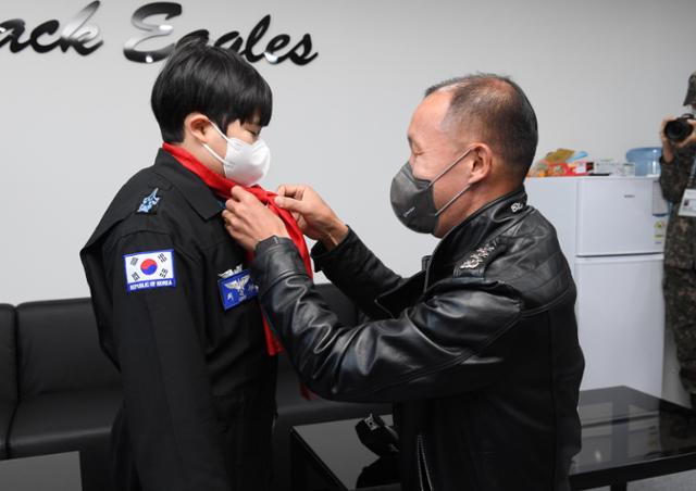 블랙이글스 전대장 김대은 대령이 21일 블랙이글스 일일 요원으로 임명된 최윤수(왼쪽)군에게 빨간마후라를 수여하고 있다. 공군 제공