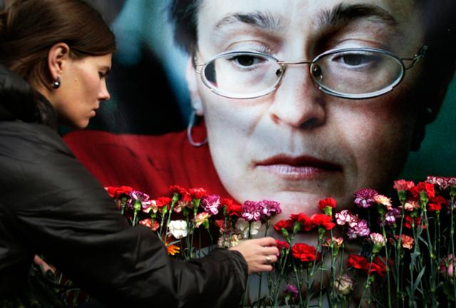 2009년 10월 7일 한 여성이 모스크바에서 살해된 러시아 언론인 안나 폴리트코프스카야의 초상화 앞에 꽃을 놓고 있다. AP 연합뉴스