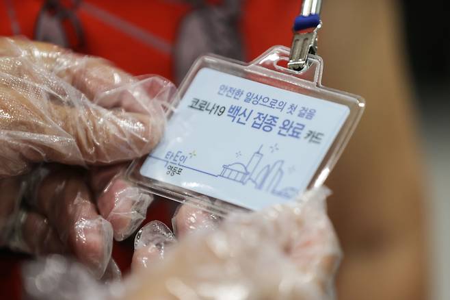지난 17일 오전 서울 영등포구 영등포아트홀에 마련된 코로나19 예방접종센터에서 한 어르신이 백신 접종 완료 카드를 보고 있다./연합뉴스