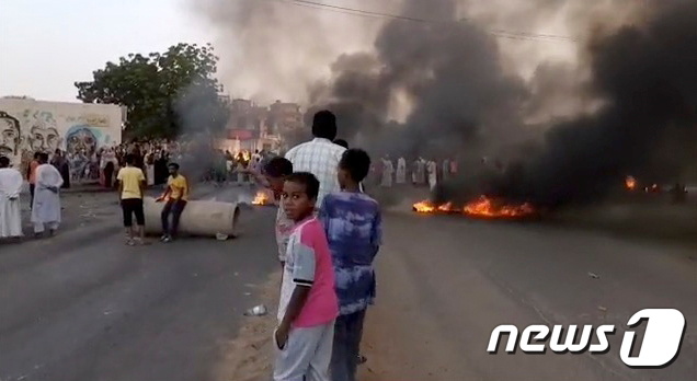 25일(현지시간) 쿠데타가 보고된 수단의 하르툼 거리에서 연기와 화재가 보이자 사람들이 모여들고 있다. © 로이터=뉴스1 © News1 노선웅 기자