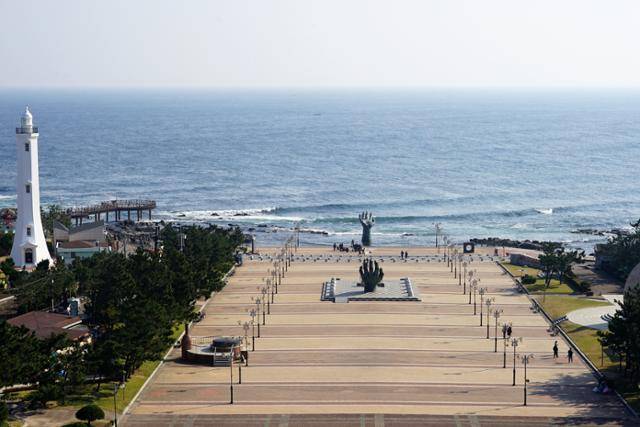 경북 포항시 남구 호미곶면에 위치한 호미곶 해맞이 광장. 우뚝 솟은 하얀 건물은 113년의 역사를 자랑하는 호미곶 등대이고, 광장 한가운데와 바다 위로 해를 떠받치는 형태의 조형물은 호미곶을 상징하는 '상생의 손'이다. 김정혜 기자