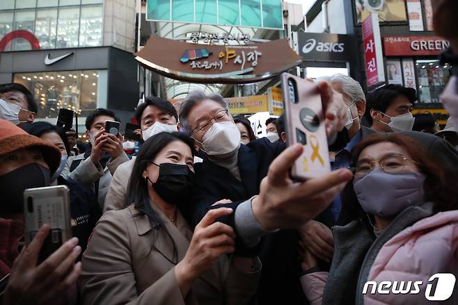 전국 민생탐방 투어에 나선 이재명 더불어민주당 대선 후보가 12일 오후 울산 중구 울산중앙전통시장을 방문해 시민들과 셀카를 찍고 있다. 이 후보는 이날 부산·울산·경남을 시작으로 약 8주간 버스를 타고 전국 곳곳의 목소리를 경청하는 매타버스(매주 타는 민생버스) 프로젝트에 돌입했다. 2021.11.12/뉴스1 © News1 오대일 기자