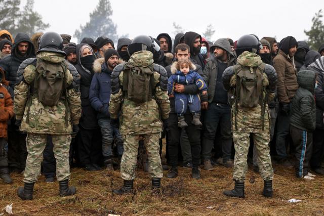 시리아 등 중동에서 건너온 이민자들이 14일 폴란드·벨라루스 접경지역인 벨라루스 그로드노에서 군인들과 대치하고 있다. 그로드노=AP 연합뉴스